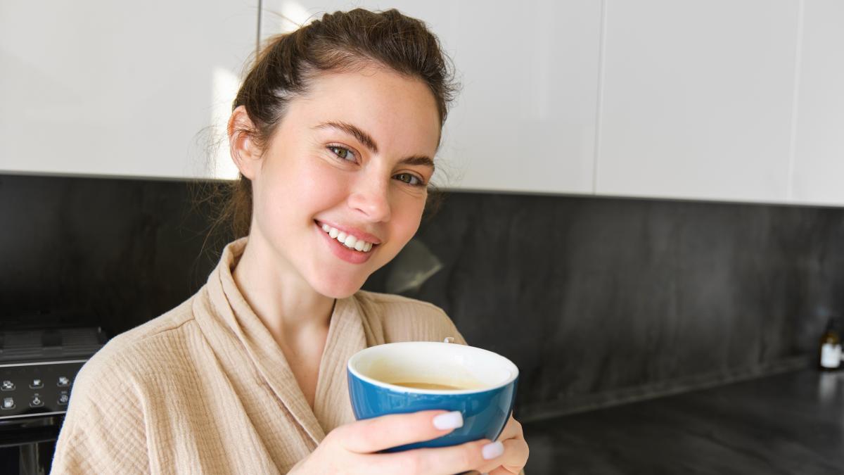 close-up-portrait-beautiful-smiling-woman-holding-cup-coffee-posing-kitchen-enjoying_72991400