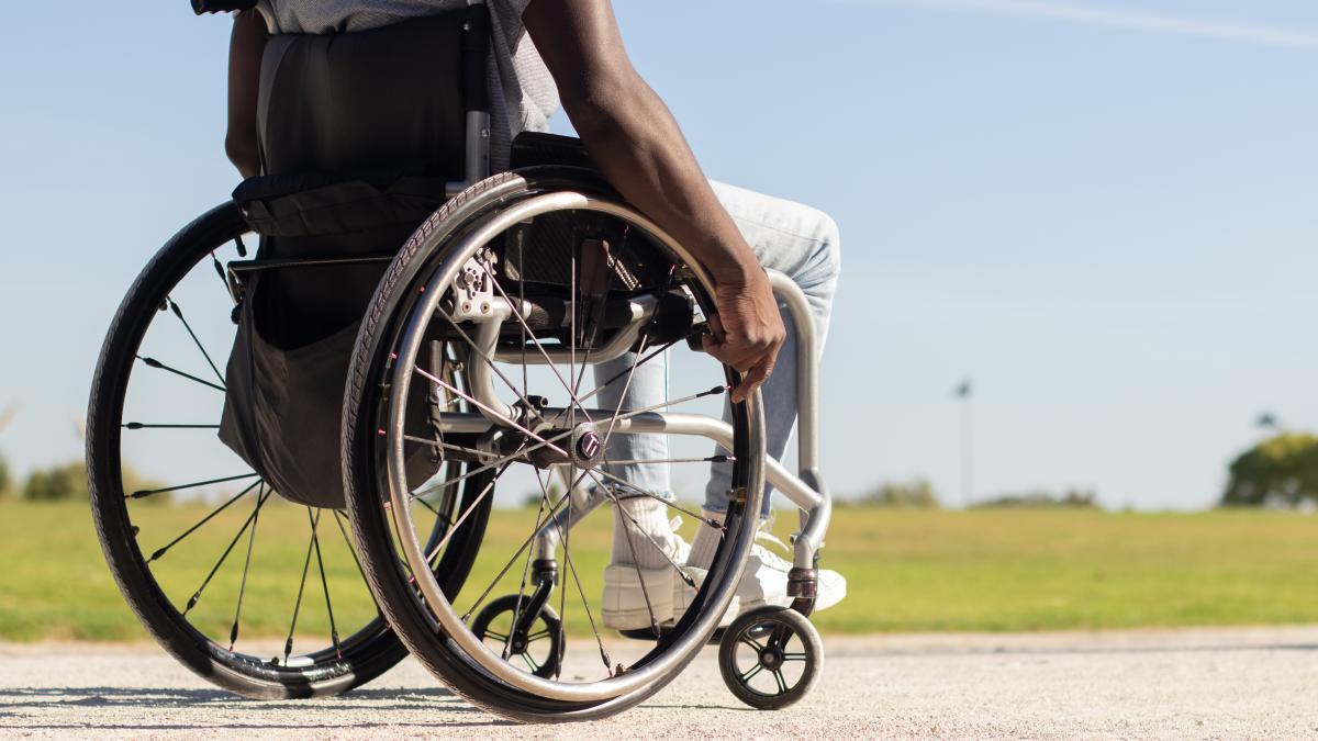 black-man-wheelchair-riding-along-park-road_77313000