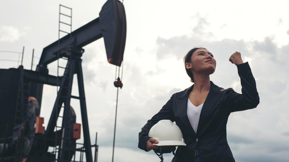 female-engineer-standing-with-working-oil-pumps-with-white-sky_57656300