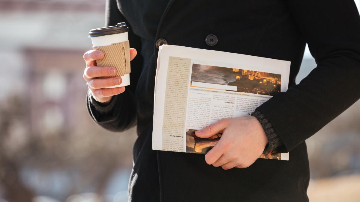 man-with-coffee-newspaper-walking-city_22629700