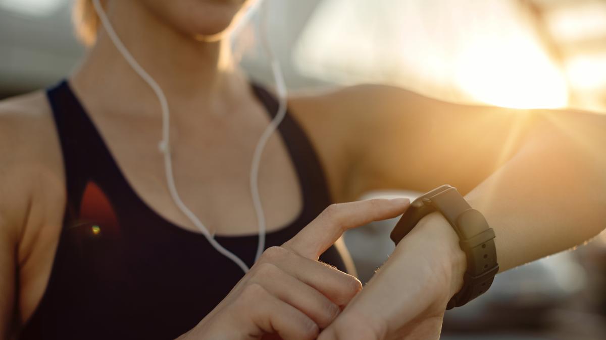 closeup-athletic-woman-using-fitness-tracker-sunset_48534900