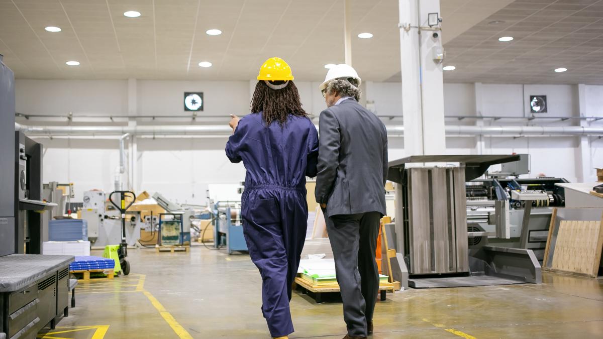 rear-view-boss-standing-factory-listening-plant-worker_89960100