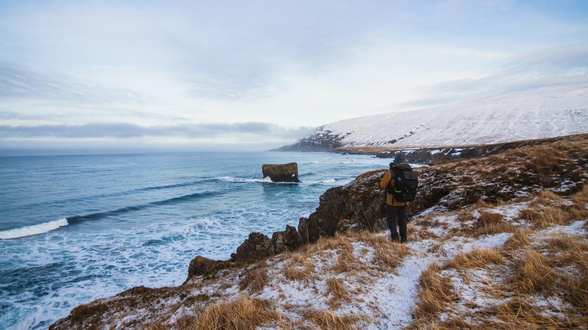 person-standing-hills-covered-snow-surrounded-by-sea-iceland_79523800
