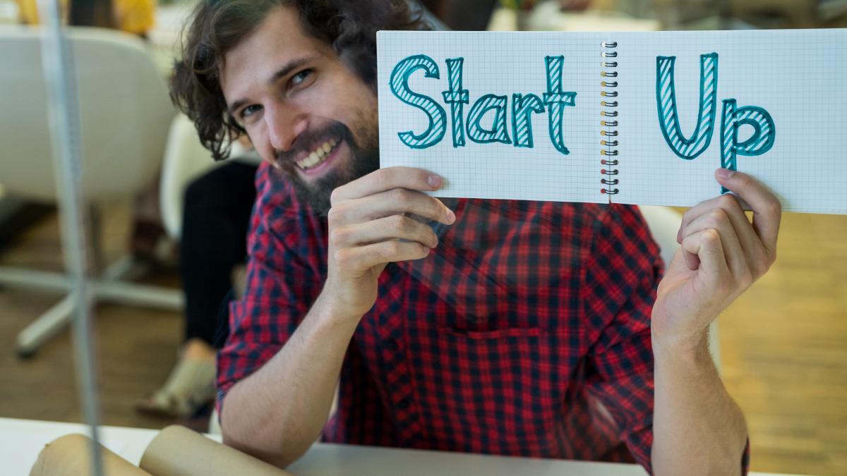 male-graphic-designer-holding-spiral-notepad-with-text_30859700