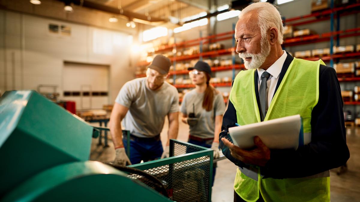 senior-businessman-taking-notes-while-inspecting-workers-who-are-working-machine-factory-warehouse_58782700