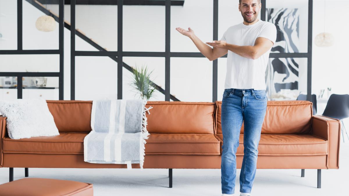 guy-standing-showing-his-living-room_42959900
