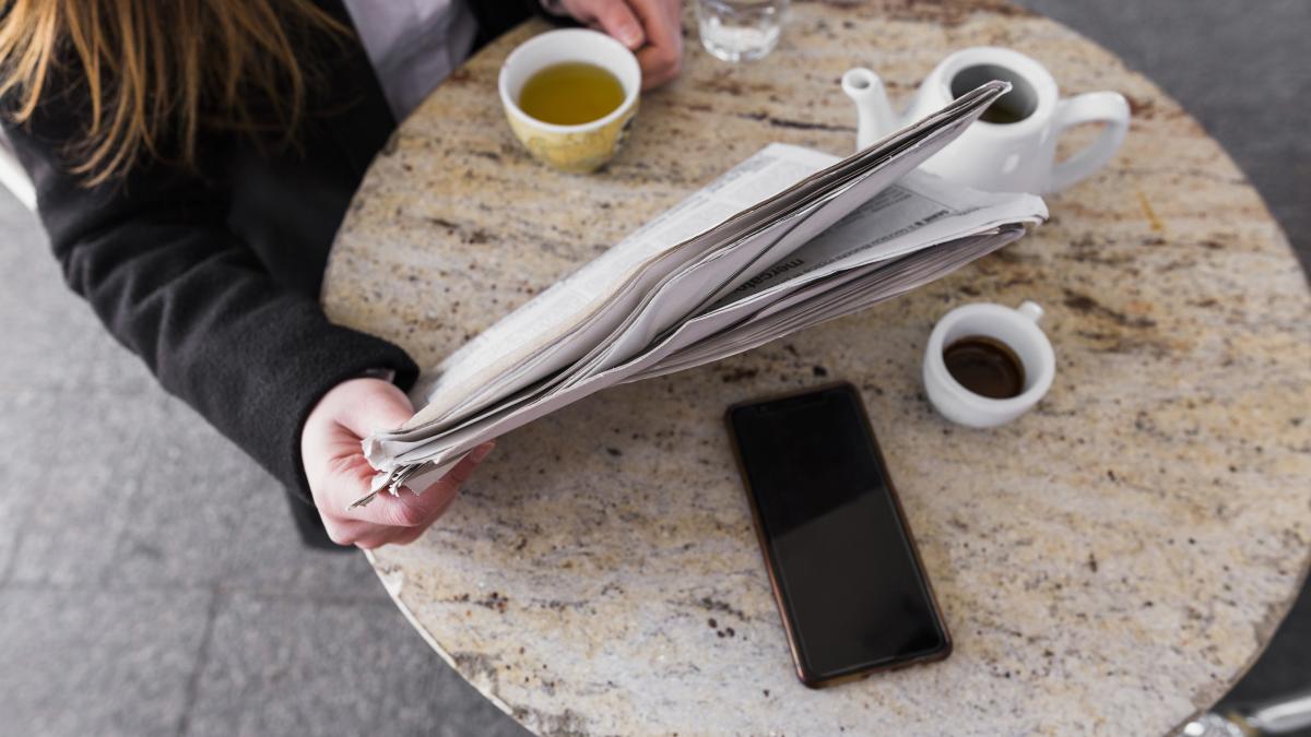 woman-drinking-tea-reading-newspaper-table_04231900