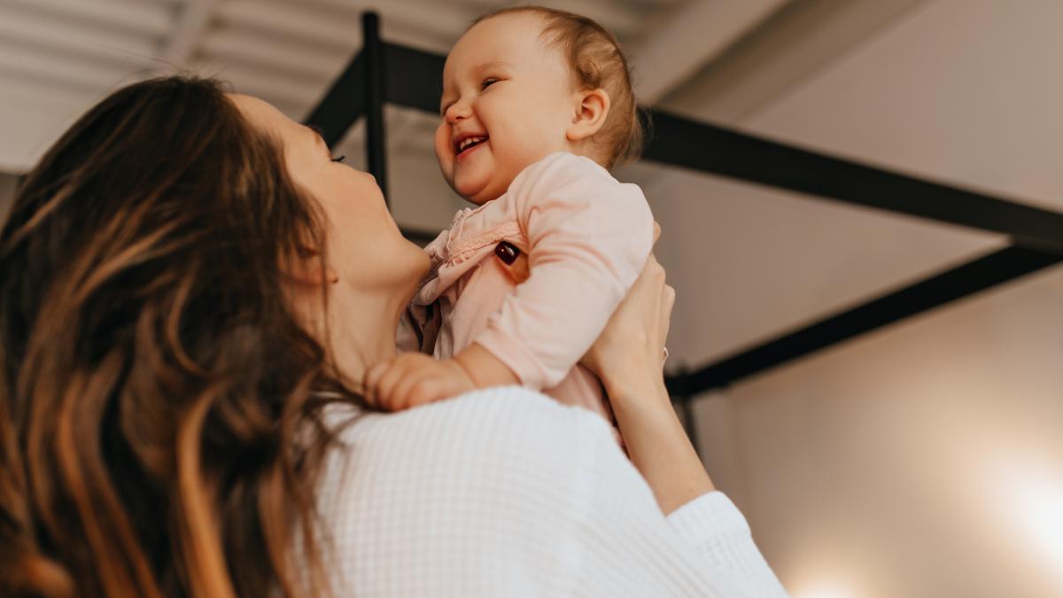 woman-with-long-hair-tickles-throws-up-laughing-baby-light-colored-home-sweater_34669500