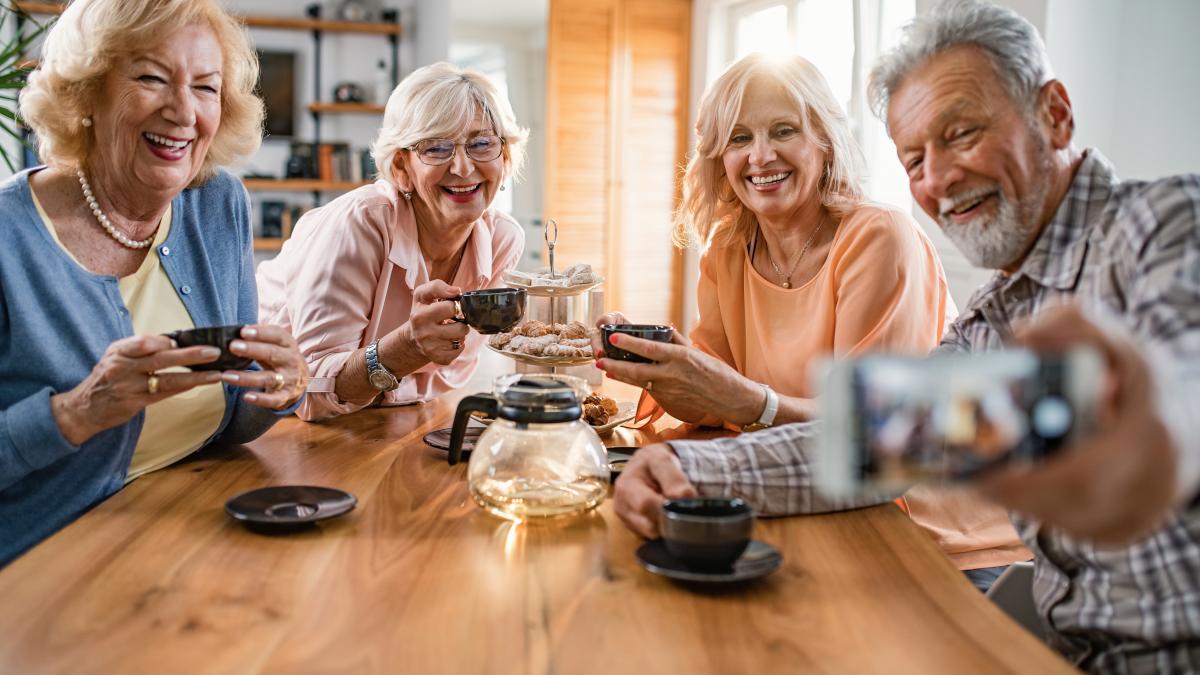 happy-mature-friends-having-fun-while-using-mobile-phone-talking-selfie-home_85890600