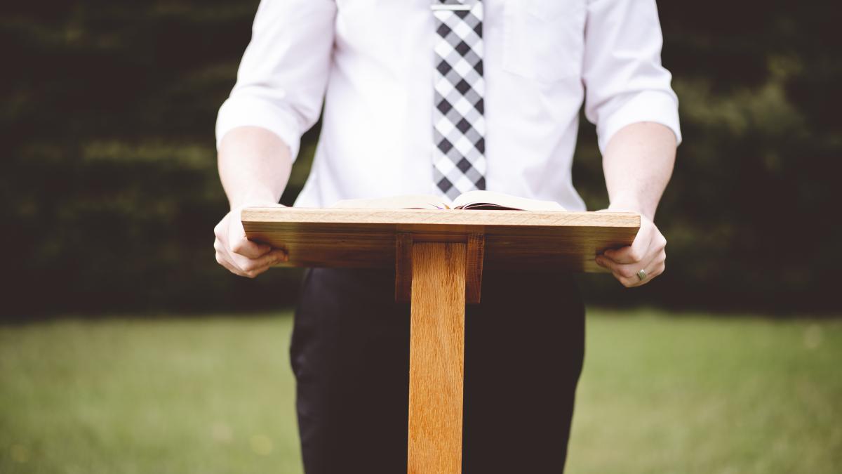closeup-shot-male-front-speech-stand-with-opened-book_39591500