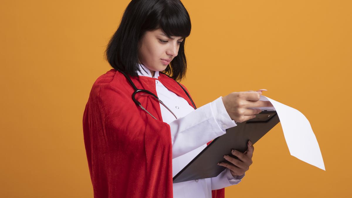 confused-young-superhero-girl-wearing-stethoscope-with-medical-robe-cloak-flipping-through-clipboard_35204800