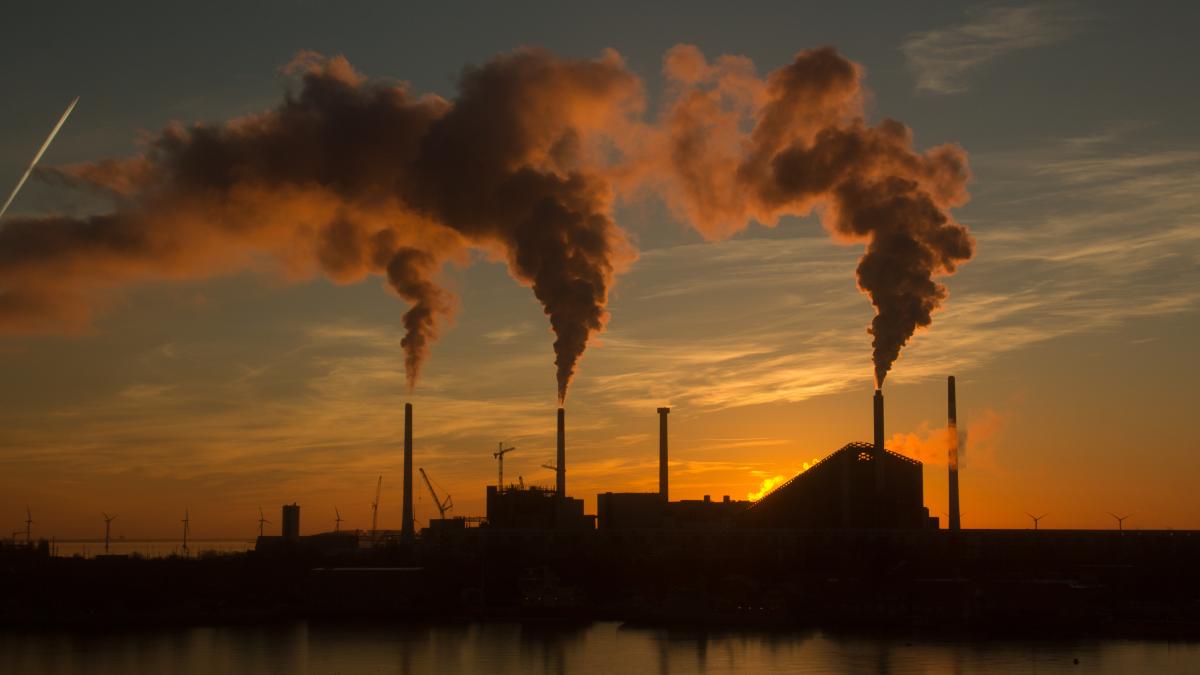 low-angle-shot-factory-with-smoke-steam-coming-out-chimneys-captured-sunset_66887400