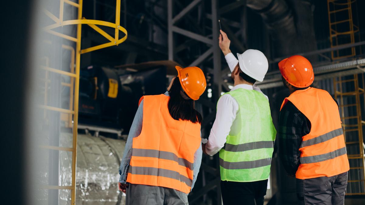 three-factory-workers-safety-hats-discussing-manufacture-plan_98246800