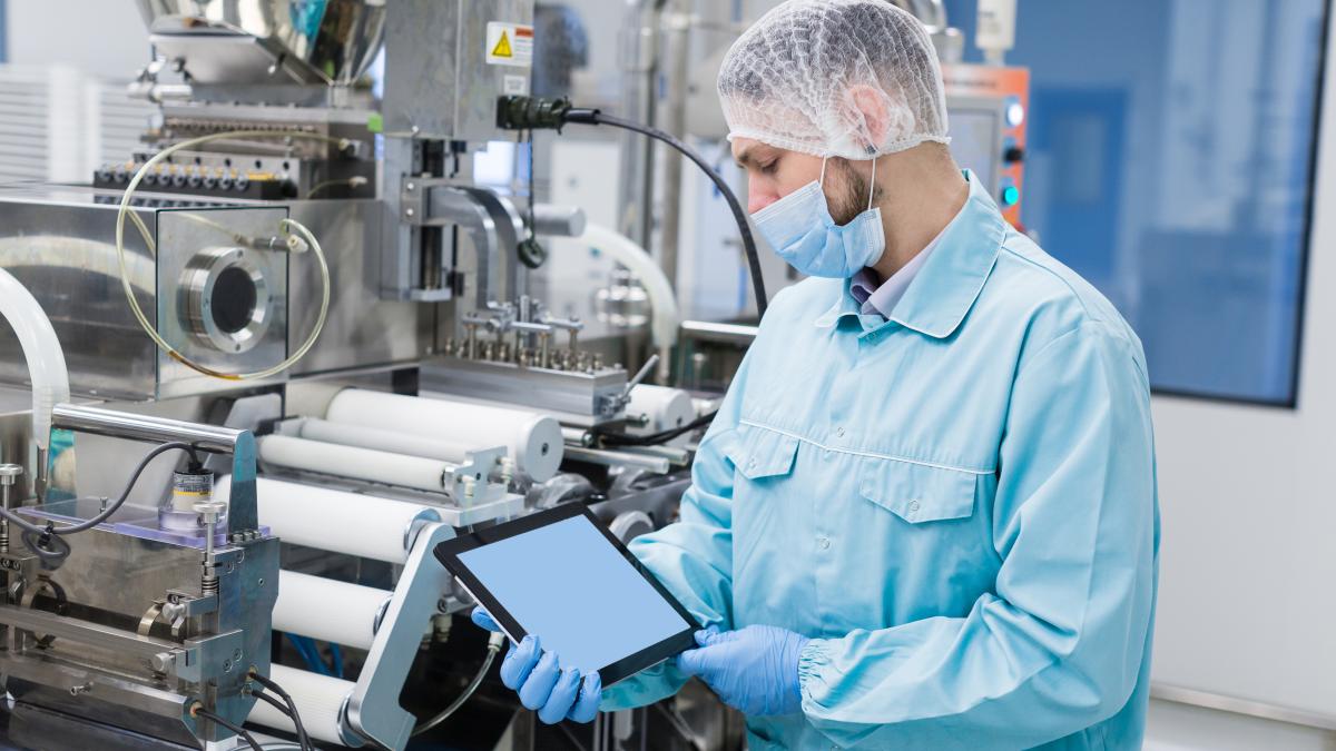 caucasian-scientist-man-blue-lab-uniform-stand-near-manufacture-machine-with-shafts-show-empty-tablet-close-picture-focus-tablet-look-tablet_93261700