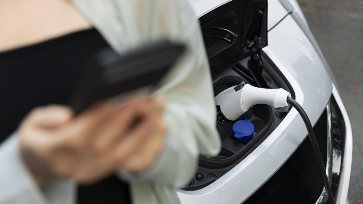woman-using-her-smartphone-while-electric-car-is-charging_28457400