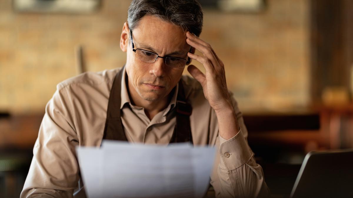 distraught-small-business-owner-reading-reports-while-going-through-paperwork-bar_13625900