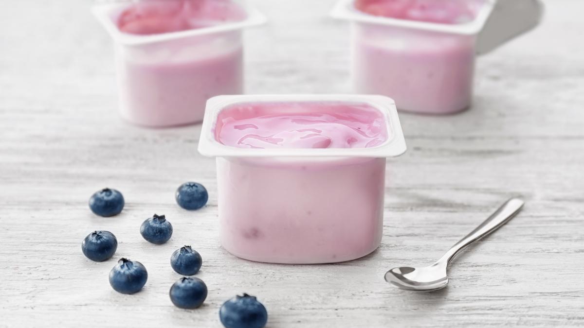 plastic-cup-with-yogurt-blueberries-wooden-table_16965800