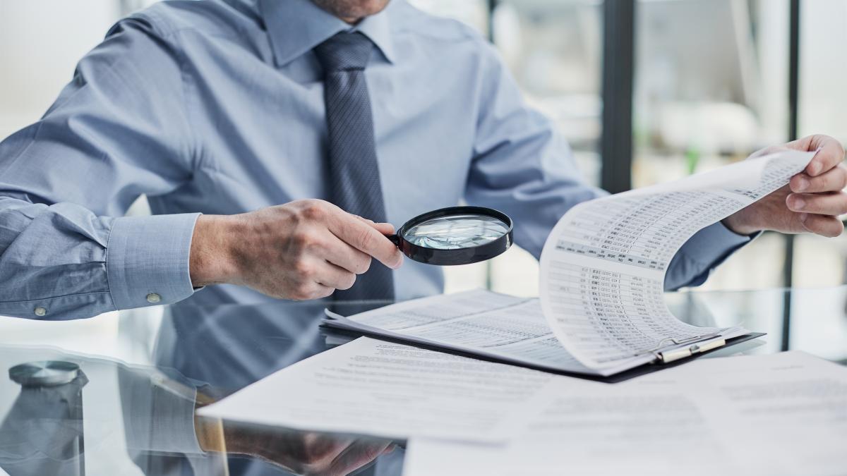 businessman-looking-through-magnifying-glass-documents_68613600