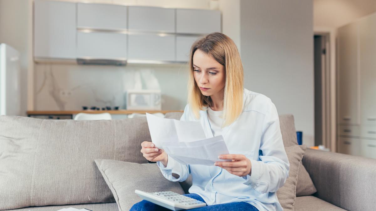 worried-housewife-pays-inflated-bills-while-sitting-sofa-home-frustrated-with-work-monthly-income_16672800