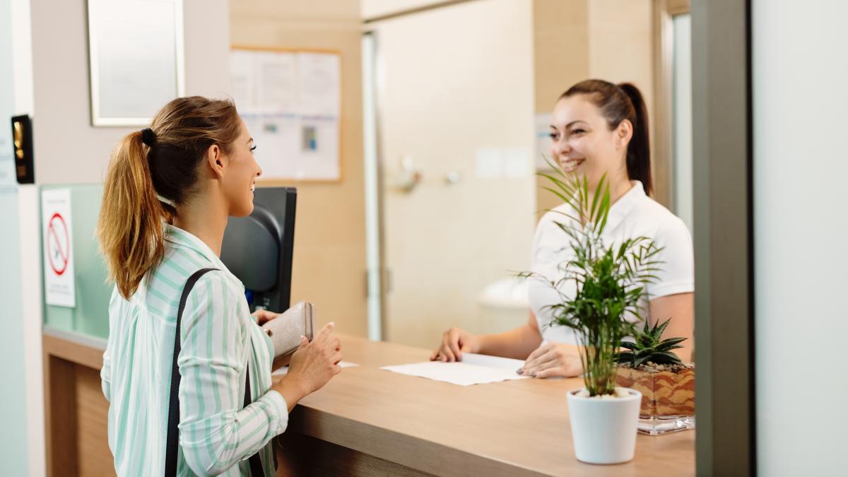 happy-woman-talking-receptionist-while-arriving-spa_42497000