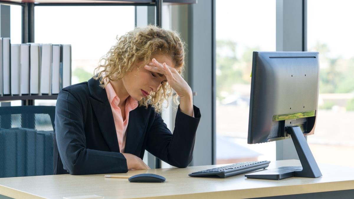 businesswoman-with-head-hands-sitting-desk_73917400