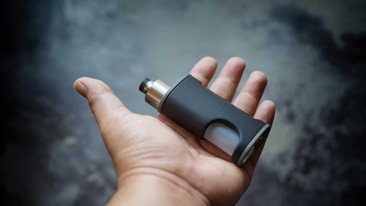 cropped-hand-holding-electronic-cigarette-against-wall_92054300